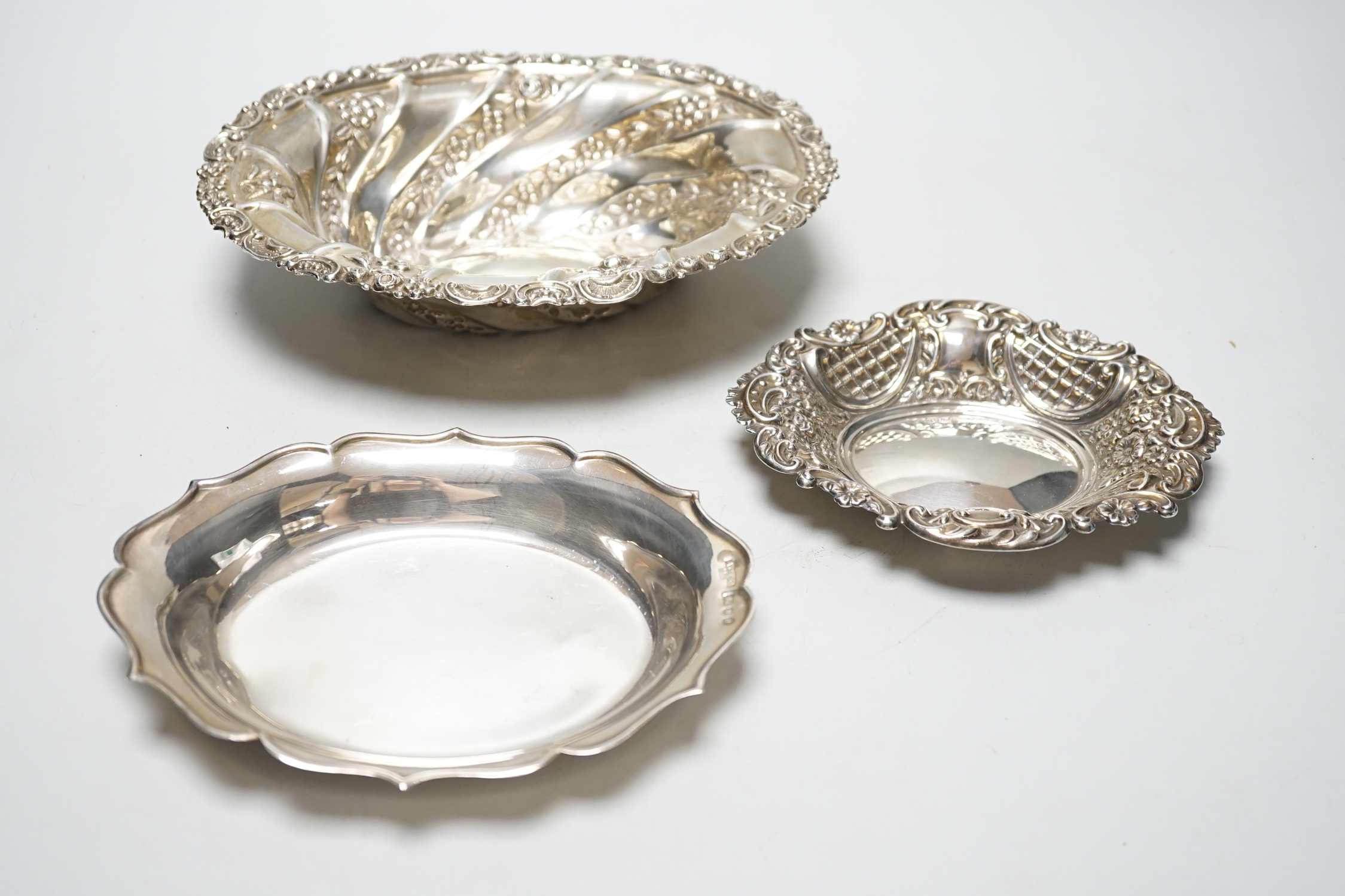 A late Victorian repousse silver oval bowl, William Comyns, London, 1889, 21.1cm and two other smaller silver dishes, 10.8oz.